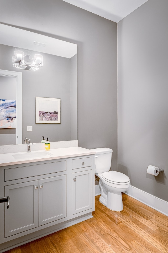 bathroom with vanity, toilet, and hardwood / wood-style flooring