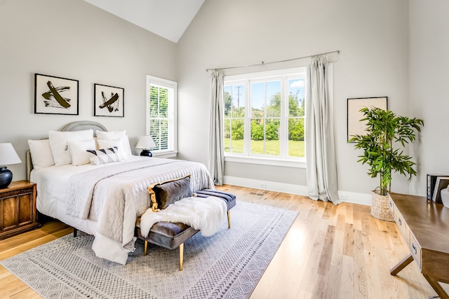 bedroom with light wood-type flooring and high vaulted ceiling