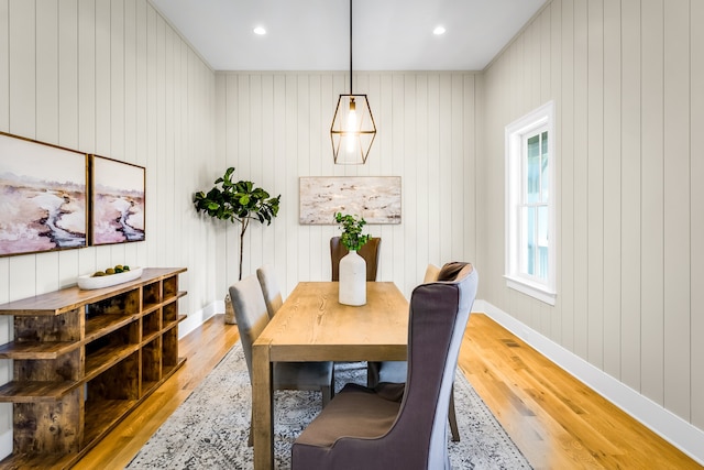 dining area with wood walls and light hardwood / wood-style flooring