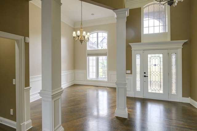 foyer with a high ceiling, an inviting chandelier, dark hardwood / wood-style floors, and ornate columns