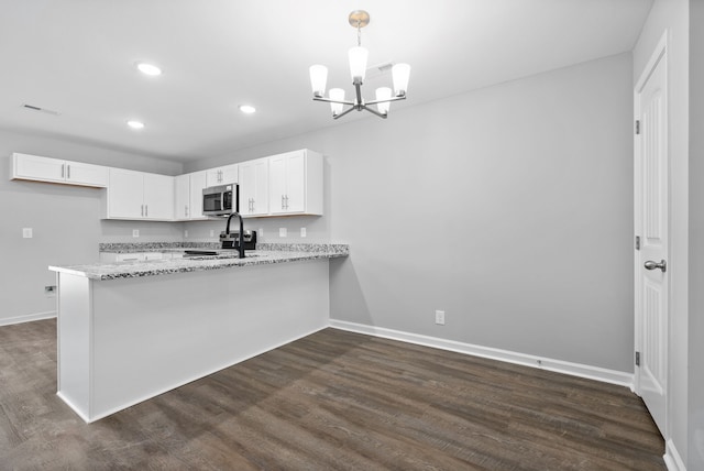 kitchen with stainless steel appliances, light stone counters, kitchen peninsula, and white cabinets