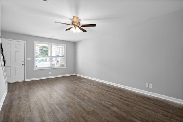 spare room featuring baseboards, ceiling fan, and dark wood-style flooring