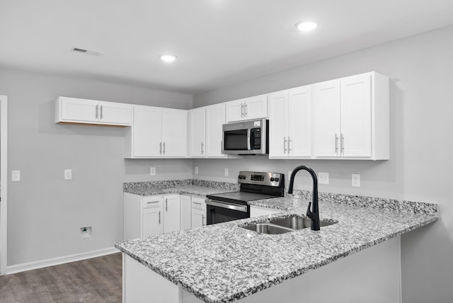 kitchen featuring light stone counters, kitchen peninsula, sink, appliances with stainless steel finishes, and white cabinets