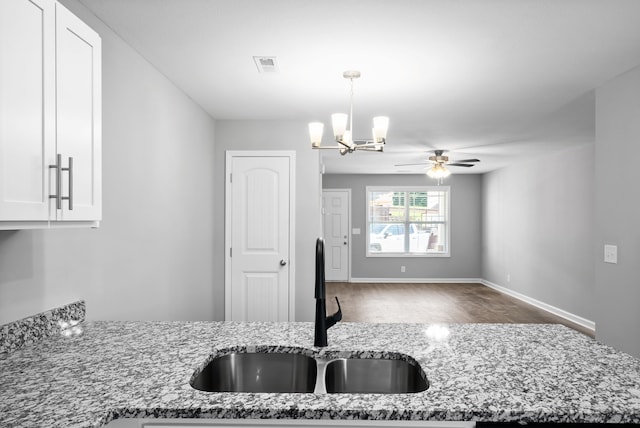 kitchen with pendant lighting, stone counters, wood-type flooring, sink, and ceiling fan