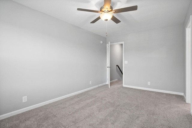 carpeted empty room featuring baseboards and a ceiling fan