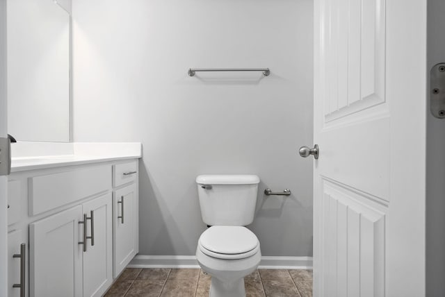 half bathroom featuring vanity, tile patterned floors, toilet, and baseboards