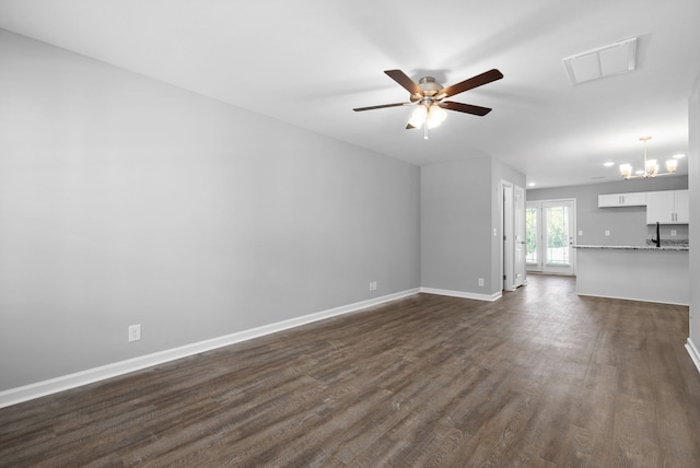 unfurnished living room with dark wood-type flooring and ceiling fan with notable chandelier