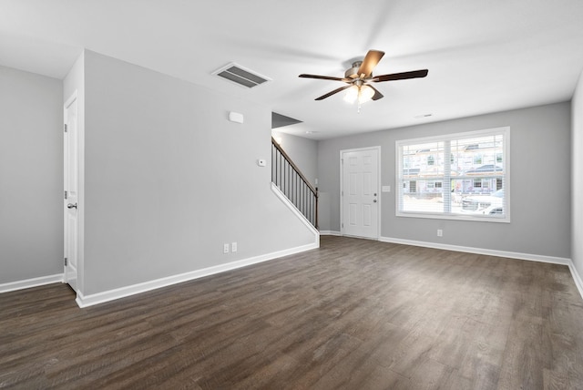 unfurnished living room featuring visible vents, dark wood-type flooring, baseboards, stairs, and a ceiling fan