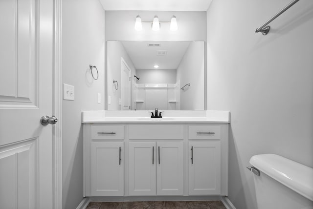 bathroom with vanity, toilet, and a shower