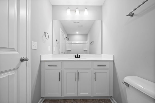 bathroom featuring visible vents, toilet, a shower, baseboards, and vanity