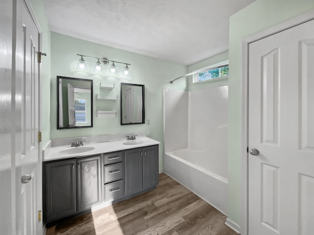 bathroom with vanity, a textured ceiling, hardwood / wood-style floors, and bathtub / shower combination