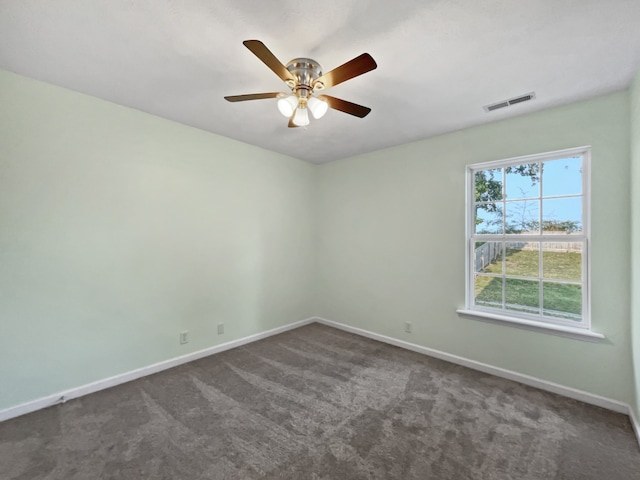 spare room with ceiling fan and dark colored carpet