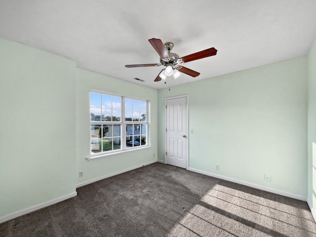 empty room with dark colored carpet and ceiling fan