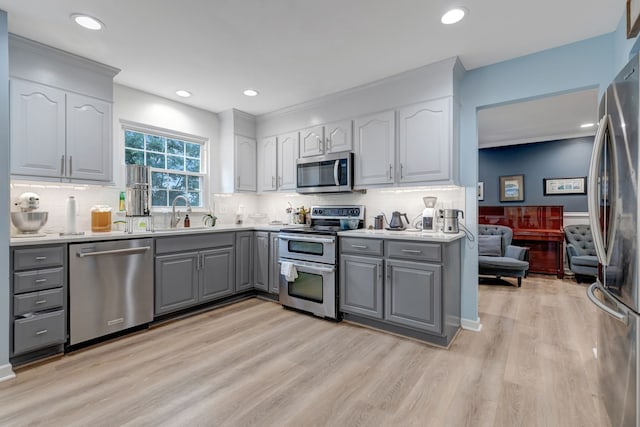 kitchen with light hardwood / wood-style flooring, stainless steel appliances, sink, and gray cabinets