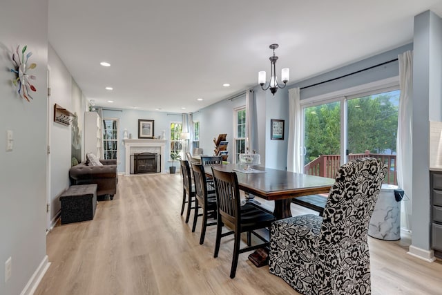 dining room featuring a premium fireplace, an inviting chandelier, and light hardwood / wood-style floors