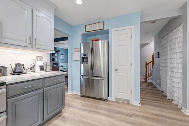 kitchen featuring gray cabinetry, light hardwood / wood-style floors, white cabinetry, stainless steel refrigerator with ice dispenser, and decorative backsplash