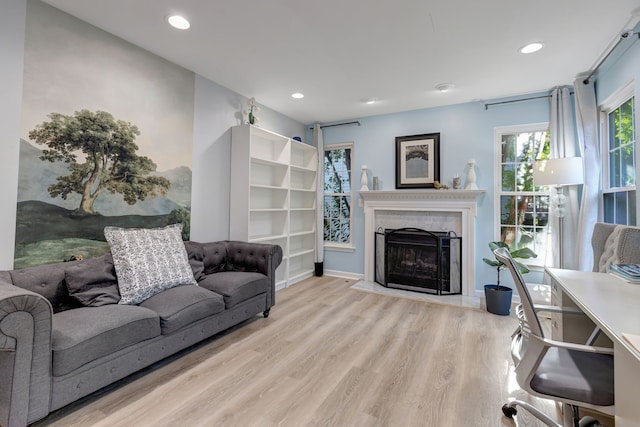 living room with light wood-type flooring and a tiled fireplace