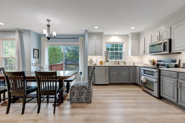 kitchen featuring a chandelier, stainless steel appliances, gray cabinetry, and light hardwood / wood-style floors