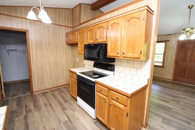 kitchen with hardwood / wood-style floors, white range with electric stovetop, ceiling fan with notable chandelier, tile countertops, and wood walls