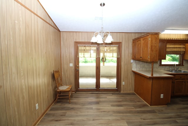 kitchen featuring wood walls, pendant lighting, a notable chandelier, hardwood / wood-style floors, and sink