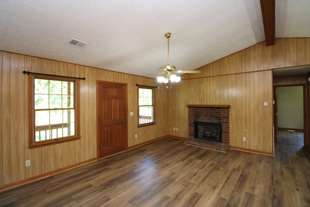 unfurnished living room with ceiling fan, a wealth of natural light, dark hardwood / wood-style flooring, and a brick fireplace