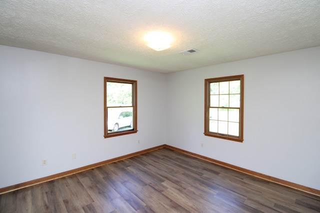 empty room featuring dark wood-type flooring and a textured ceiling