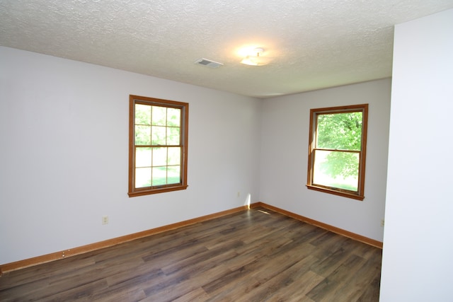 spare room with dark wood-type flooring, a textured ceiling, and a healthy amount of sunlight