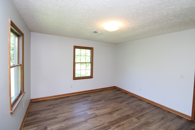 spare room with plenty of natural light, dark hardwood / wood-style flooring, and a textured ceiling