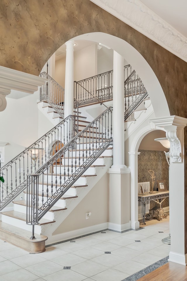 stairs featuring tile patterned floors and ornate columns