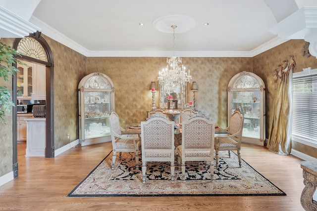 dining room with light wood-type flooring, a notable chandelier, and ornamental molding