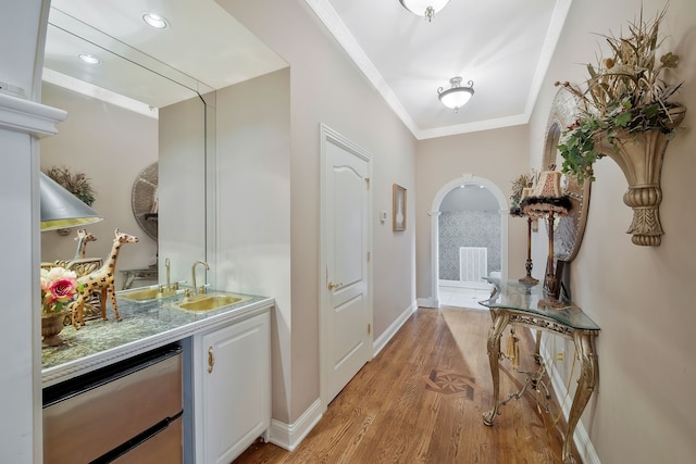 doorway to outside with crown molding, sink, and light wood-type flooring