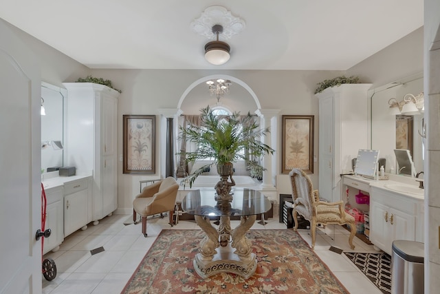 bathroom with decorative columns, sink, an inviting chandelier, and tile patterned floors