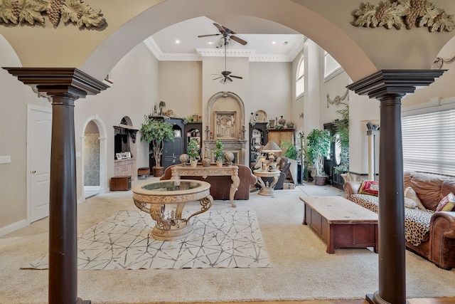 living room featuring a towering ceiling, ornamental molding, ceiling fan, and carpet floors