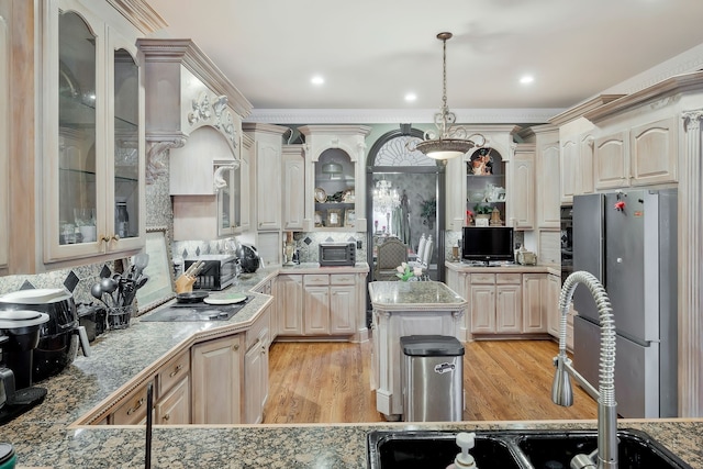 kitchen featuring light hardwood / wood-style flooring, sink, hanging light fixtures, appliances with stainless steel finishes, and ornate columns