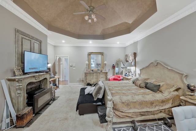 carpeted bedroom featuring a tray ceiling, crown molding, and ceiling fan