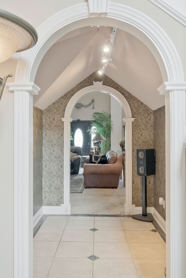 hallway featuring lofted ceiling, ornate columns, and light tile patterned flooring