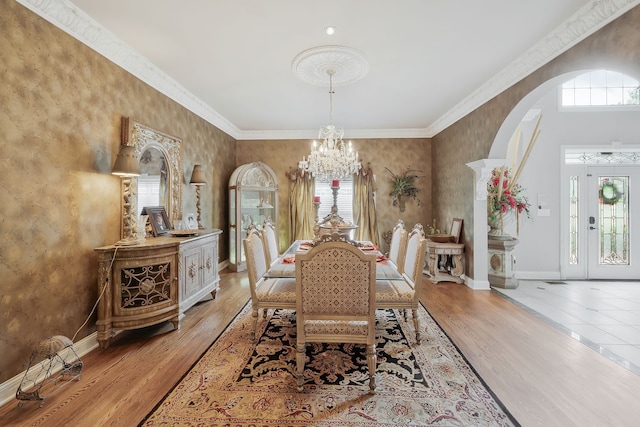 dining room with a wealth of natural light, ornamental molding, a chandelier, and light hardwood / wood-style flooring