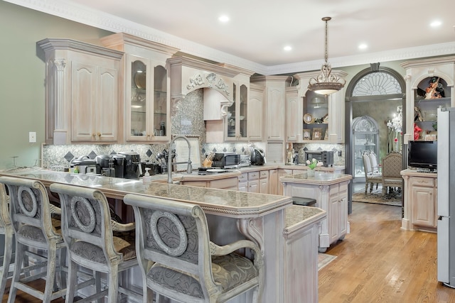 kitchen featuring a center island, decorative light fixtures, light hardwood / wood-style floors, kitchen peninsula, and a kitchen breakfast bar