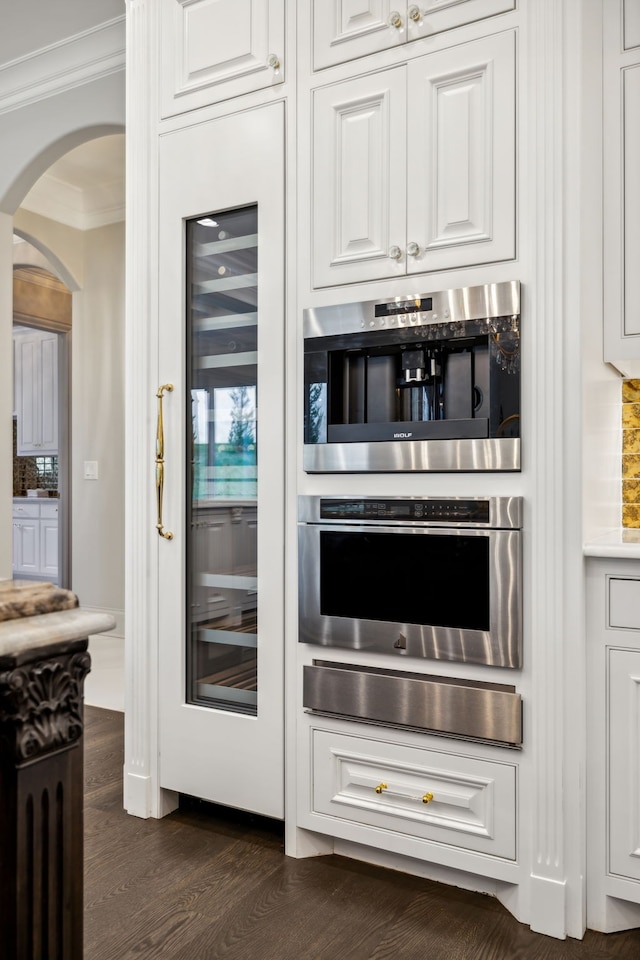 bar with backsplash, dark hardwood / wood-style flooring, white cabinetry, and ornamental molding