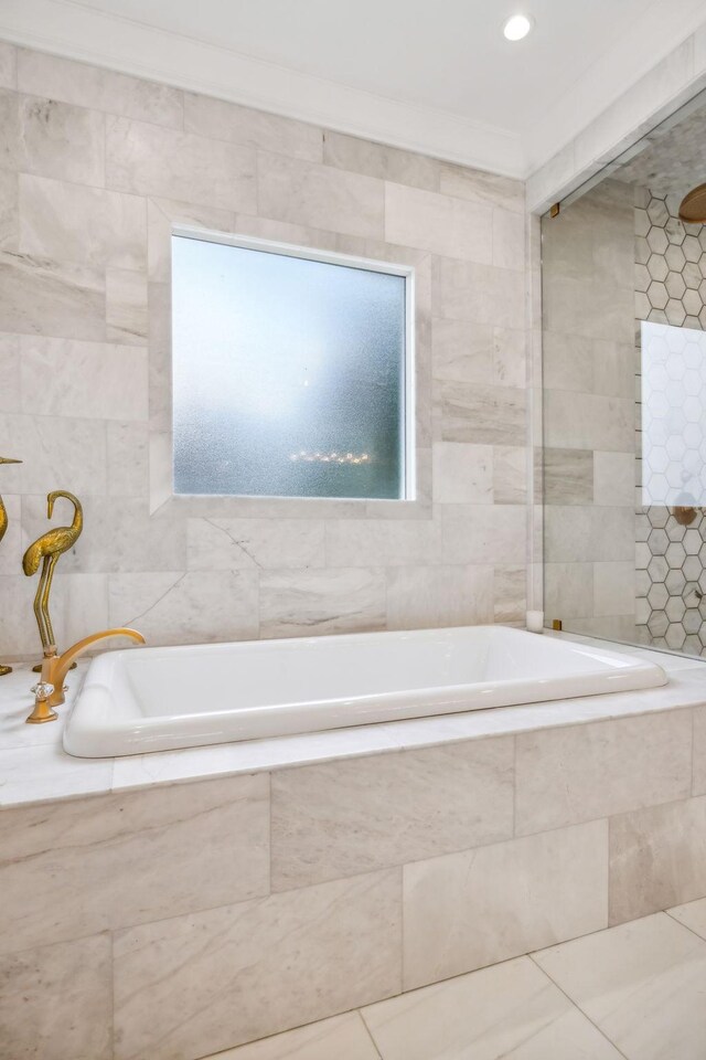 bathroom featuring tile walls, plenty of natural light, a relaxing tiled tub, and tile patterned flooring