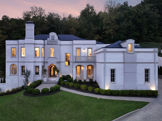 view of front of home featuring a lawn and a balcony