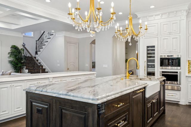 kitchen featuring a kitchen island with sink, dark wood-type flooring, ornamental molding, and a notable chandelier