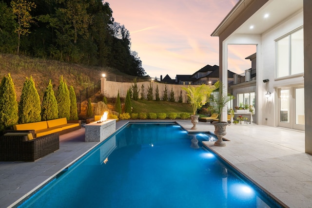 pool at dusk featuring an outdoor fire pit and a patio area