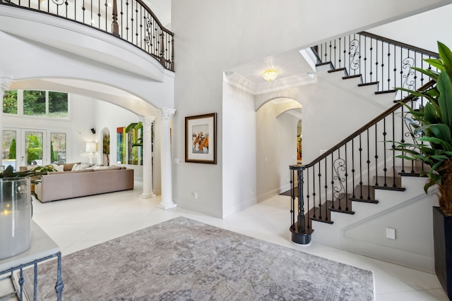 tiled foyer with a high ceiling and decorative columns