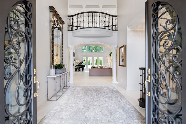 tiled foyer entrance with a towering ceiling and decorative columns