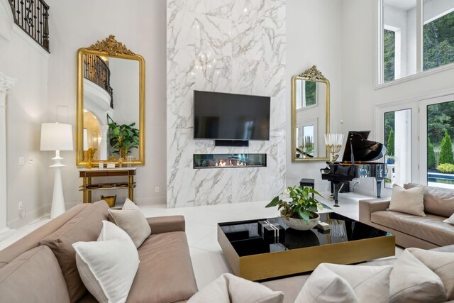 living room featuring a fireplace, a healthy amount of sunlight, and a high ceiling