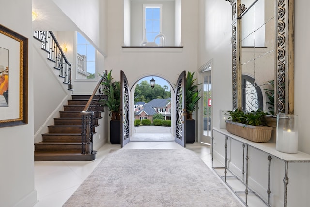 foyer entrance featuring a towering ceiling and light tile patterned flooring