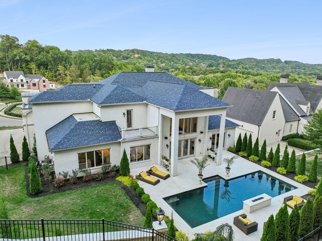 rear view of house featuring a balcony, a fenced in pool, a lawn, and a patio