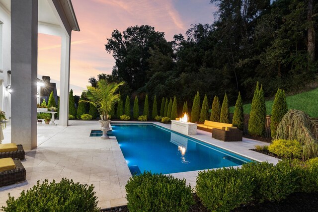 pool at dusk with a patio area