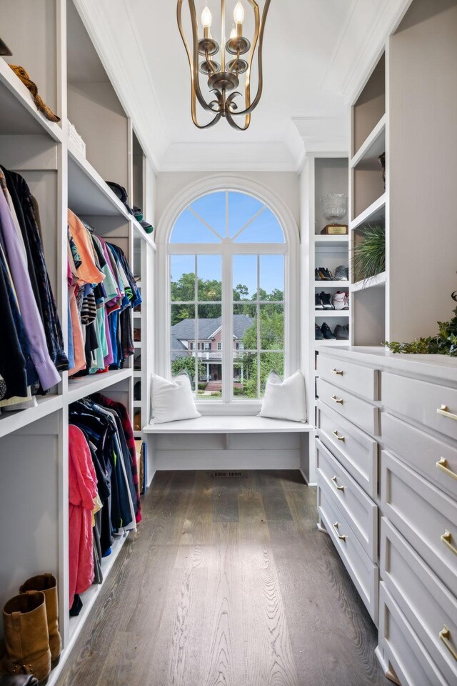 spacious closet with dark wood-type flooring and a notable chandelier